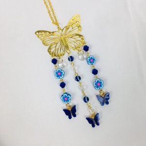 Detailed shot of golden hollow butterfly pendant with blue crystal beads on hanging chains