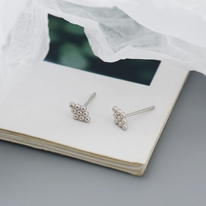Macro shot of silver S925 geometric bead triangle stud earrings on a vintage book page