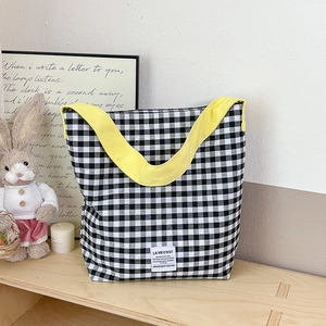 Gros plan du sac en toile à carreaux noir et blanc avec une bandoulière jaune vif