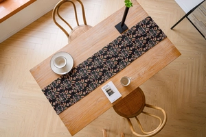 Close-up of black floral jacquard table runner with white ceramic dinnerware set