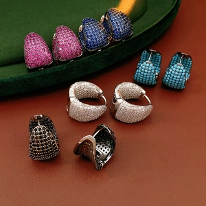 Detailed macro shot of C-shaped earrings with colorful cubic zirconia on velvet
