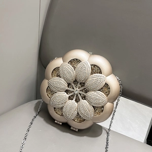 Macro shot of luxury champagne gold flower evening bag with sparkling rhinestones and silver chain