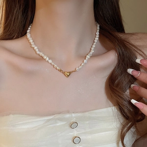Detailed view of 18K gold heart pendant on irregular freshwater pearl beaded necklace
