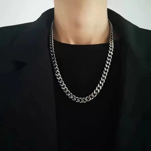 Polished silver stainless steel Cuban link chain necklace worn by male model in black suit