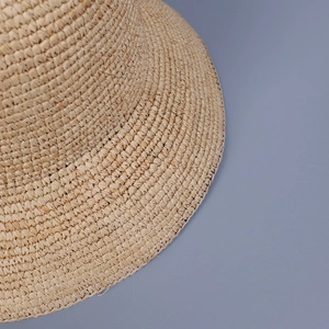 Gros plan détaillé de la texture fine du raphia tissé main sur un chapeau de soleil
