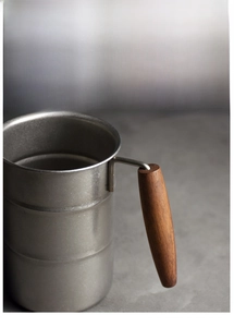 Close-up of industrial style stainless steel mug with natural wooden anti-scald handle