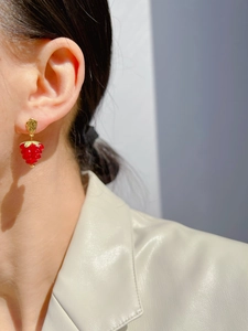 Side view of a model wearing red glass raspberry drop earrings with gold hooks