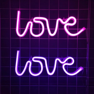 Dual-color pink and purple LED neon LOVE signs hanging on a modern metal grid wall