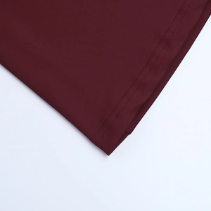 Détail de la couture à double aiguille sur le tissu bordeaux de la robe de soirée