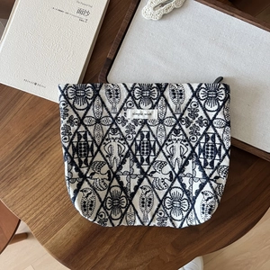 Detailed close-up of intricate bird and floral embroidery on a cotton canvas makeup bag