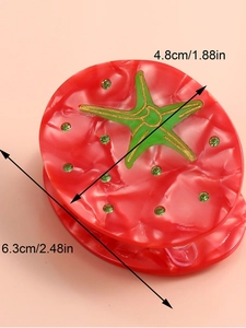 Detail view of a tomato red acetate hair claw with green star and rhinestone accents