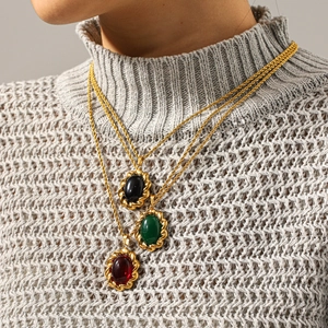 Detailed view of vintage French style stainless steel gemstone pendants on a knit sweater.