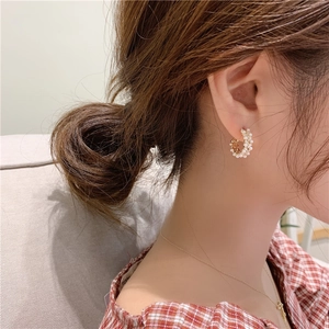 Elegant C-shaped pearl drop earrings with gold finish worn by a model in profile