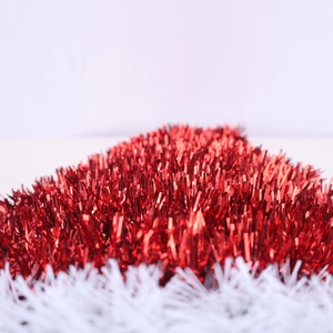 Detailed close-up of festive red metallic tinsel and soft white plush Christmas garland