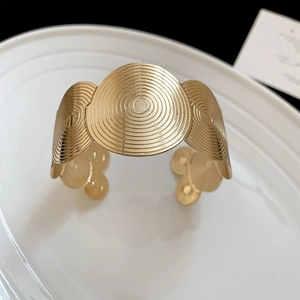 Detailed macro view of gold-finished geometric cuff bracelet with concentric circle textures