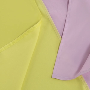 Macro detail of high-quality sewing stitches on neon yellow and light purple fabric