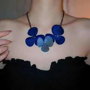 Close-up of blue resin triple flower pendant necklace worn on a fashion model's collarbone