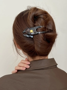 Detail of grey marble claw clip with gold fashion plate securing a high bun hairstyle