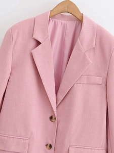 Detail of pink blazer with peak lapels, double buttons and flap pockets texture