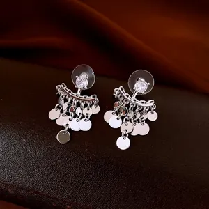 Silver fringe drop earrings with zircon circle pendant on dark leather background