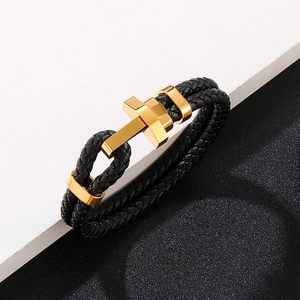 Détail du bracelet double en cuir tressé noir avec fermoir en forme de croix dorée