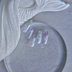 Macro shot of mermaid-themed press-on nails with 3D pearls and gradient blue glitter