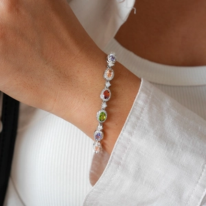 Macro detail of colorful oval gemstone bracelet with sparkling diamond halos on a wrist