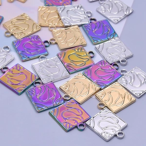 Macro shot of square swan-engraved pendants in gold, silver, and iridescent finishes