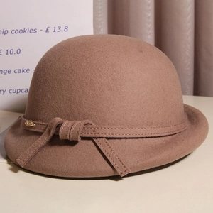 Detail of the elegant bow and gold oval metal accent on the wool cloche hat's band