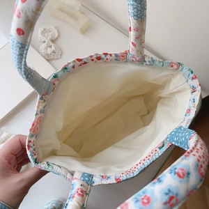 Quilted floral handbag featuring spacious cream fabric interior and light blue patterns
