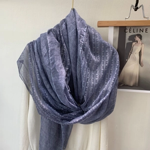 Detail of blue cotton linen scarf featuring elegant lace trim hanging on a white hanger