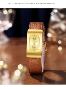 Detail view of gold rectangular case and brown leather strap on minimalist watch
