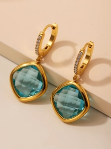 Détail de boucles d'oreilles en cristal bleu avec métal doré et pierres étincelantes