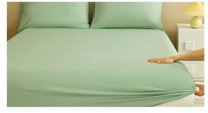 Close-up of light green elastic fitted sheet showing high stretch and soft knit fabric