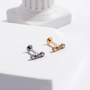 Close-up of G23 titanium labret studs with three inlaid crystals in gold and silver