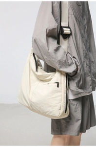 Detail of off-white nylon crossbody bag with pleated texture and adjustable strap