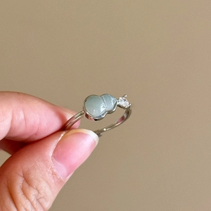 Detail of silver wavy adjustable ring with a light green gourd jade and small white diamond