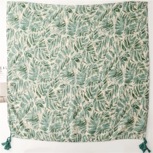 Detail of tropical green palm leaf print on lightweight fabric with teal corner tassels