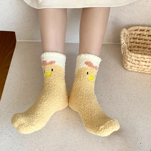 Close-up of cozy coral fleece socks featuring a cute yellow cartoon chicken embroidery