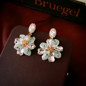 Elegant gold flower earrings with crystals and pearls on luxury leather jewelry box