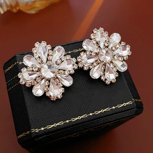 Macro detail of sparkling flower stud earrings with marquise crystals on a velvet box
