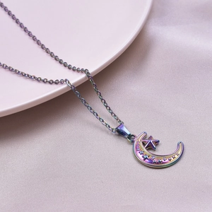 Macro shot of polished moon and star pendant with iridescent plating on silk background