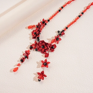 Detail of red floral acrylic pendant with black and red faceted beaded chain waist link