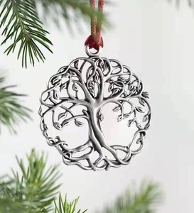 Close-up of vintage silver Tree of Life metal ornament hanging on a green pine branch