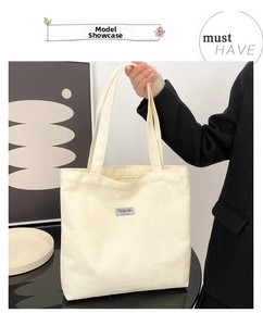 Detail of off-white thick canvas tote bag with long handles and a fashion instinct label