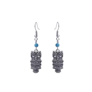 Close-up of vintage silver owl earrings featuring a blue bead and intricate bronze engraving