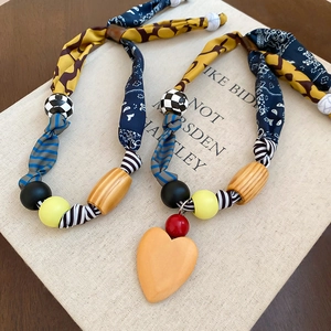 Détail de collier bohème en tissu imprimé avec pendentif en bois en forme de cœur