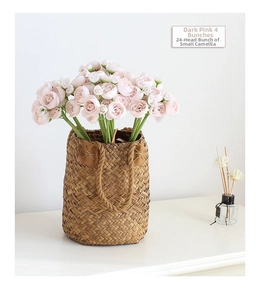 Artistic arrangement of four dark pink camellia bundles in a rustic woven basket