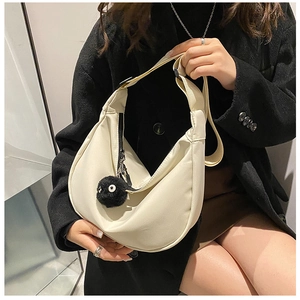 Detail of off-white crescent crossbody bag with a fuzzy soot sprite charm attachment