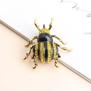 Detail of beetle brooch featuring golden alloy, black enamel, and yellow rhinestones